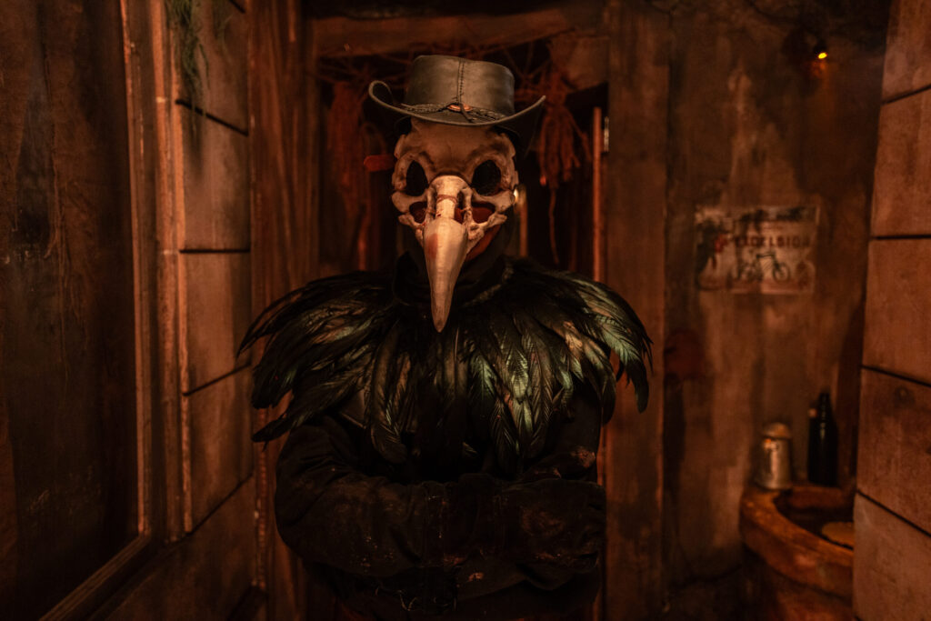 The taxidermist character - wearing a crow mask and black feathers